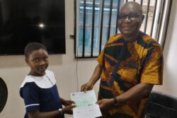 The president of the ovu foundation presenting a cheque to a student for her scholarship